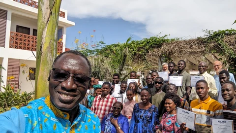 Group photo of guests & trainees (obscured by the plants), with DPTLL president François Bagne in the foreground
